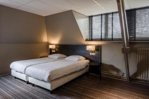 um quarto com uma grande cama branca e uma janela em Fletcher Hotel Restaurant Boschoord em Oisterwijk