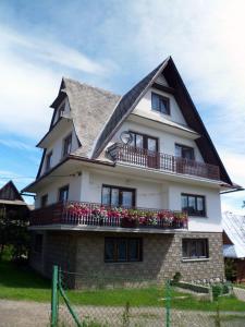 a large white house with flowers on the balcony at Pod Tatarską Górą in Biały Dunajec