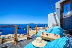 une chaise et une table bleues sur un balcon avec vue sur l'océan dans l'établissement Modernity Suites, à Fira