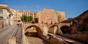 eine alte Steinbrücke in einer Stadt mit Gebäuden in der Unterkunft Plaça De La Font in Tarragona