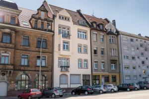 wysoki budynek z samochodami zaparkowanymi przed nim w obiekcie Family-Apartments Freiburg we Fryburgu Bryzgowijskim