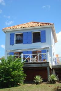 a house with blue windows and two dogs sitting on the balcony at Aloe Villa in Five Islands Village