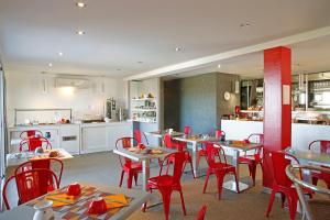 un restaurant avec des tables et des chaises rouges et une cuisine dans l'établissement Hôtel Funtana Marina, à LʼÎle-Rousse