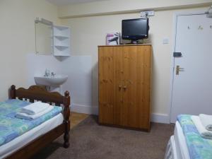 - une chambre avec 2 lits, un lavabo et une télévision dans l'établissement Longbeach- Adults Only, à Newquay