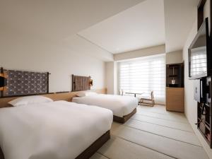 a hotel room with two beds and a television at Kyoto Granbell Hotel in Kyoto