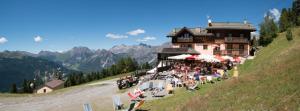 un bâtiment sur le côté d'une colline avec des tables et des chaises dans l'établissement Chalet Dei Rododendri, à Valdisotto