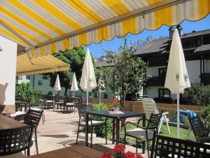 un patio con tavoli e ombrelloni bianchi di Hotel Moritz a Dobbiaco