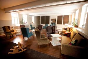 a living room with chairs and tables and a living room with at Hotel Kašperk in Kašperské Hory