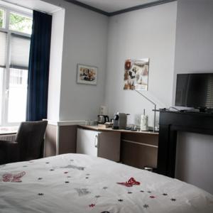 um quarto com uma cama, uma secretária e uma televisão em Het Harlekijntje em Maastricht