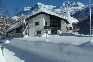 ein schneebedecktes Haus mit Bergen im Hintergrund in der Unterkunft Chesa Suot Ovas in Sils Maria