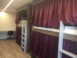 Cette chambre comprend 2 lits superposés dotés de rideaux rouges. dans l'établissement Auberge du Guintzet, à Fribourg