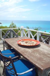 a pizza sitting on top of a wooden picnic table at Aloe Villa in Five Islands Village