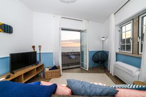 uma sala de estar com televisão e vista para o oceano em Feel Nazaré - Ocean View na Nazaré