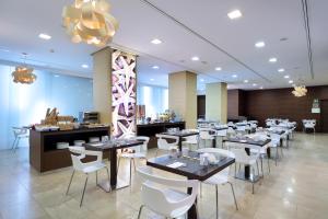 une salle à manger avec des tables et des chaises blanches dans l'établissement Eurostars Lucentum, à Alicante