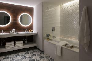 a bathroom with a tub and a sink and a mirror at The Goodwin in Hartford