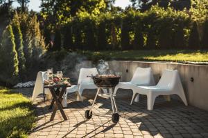 a group of white chairs and a grill on a patio at Krauklis beach apartments in Saulkrasti