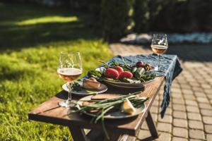 a table with two glasses of wine and a plate of food at Krauklis beach apartments in Saulkrasti