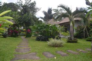 un jardín con un camino delante de una casa en Suka's House Bed & Breakfast, en Ubud