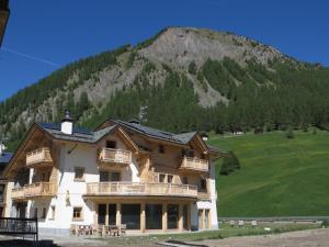 a large building with a mountain in the background at B&B Ecohotel Chalet des Alpes in Livigno