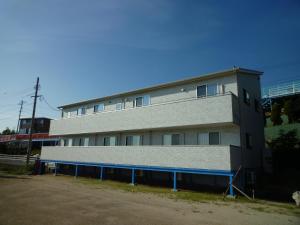 un edificio bianco con una recinzione blu davanti di Sea Side Hostel Light House a Onomichi