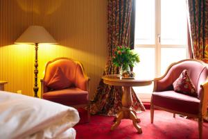 a bedroom with two chairs and a table and a bed at Landhaus Zu den Rothen Forellen in Ilsenburg