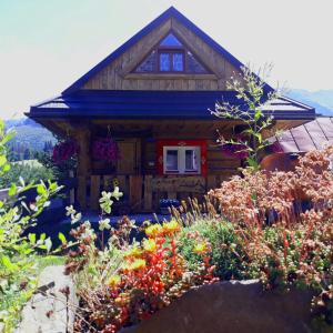 uma pequena casa de madeira com flores em frente em Zrub Niki em Ždiar