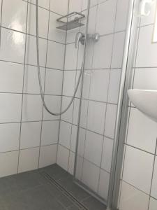 een douche in een wit betegelde badkamer met een wastafel bij Haus Heverstrom in Westerhever