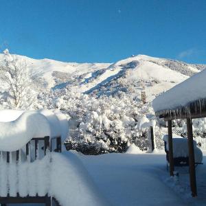 un patio cubierto de nieve con una montaña en el fondo en Cabañas Ruca Carel, en San Carlos de Bariloche