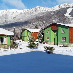 un grupo de casas en la nieve con montañas cubiertas de nieve en Cabañas Ruca Carel, en San Carlos de Bariloche