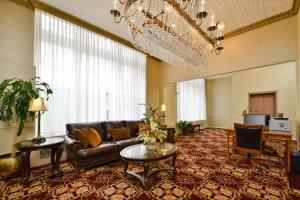 Genetti Hotel, SureStay Collection by Best Western في ويليامزبورت: غرفة معيشة مع أريكة جلدية وثريا