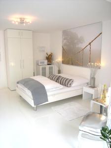 um quarto branco com uma cama e uma pintura de ponte na parede em A-Partments em Colónia