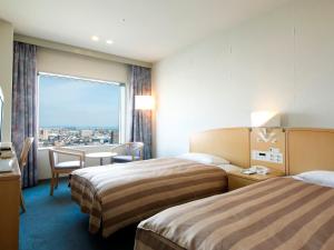 a hotel room with two beds and a large window at Tokushima Grandvrio Hotel in Tokushima