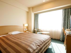 a hotel room with a bed and a large window at Tokushima Grandvrio Hotel in Tokushima