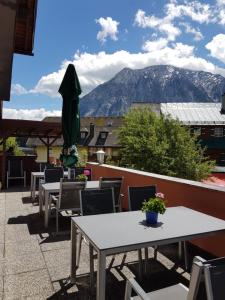 un patio con mesas, sillas y una montaña en Hotel Tauplitzerhof, en Tauplitz