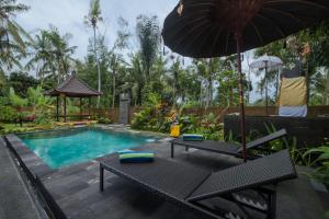 a pool with a table and an umbrella and a bench at Puri Astina Villa in Ubud