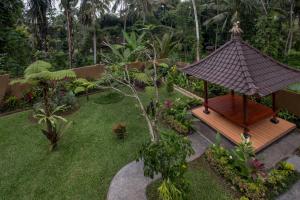 a garden with a wooden gazebo in the grass at Puri Astina Villa in Ubud