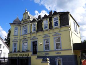 un edificio amarillo con una torre de reloj en la parte superior en Hotel Villa Schneverdingen, en Schneverdingen