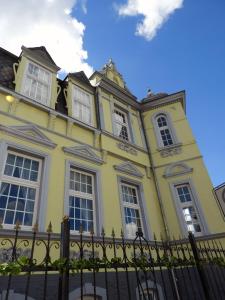 un edificio amarillo con ventanas y una valla en Hotel Villa Schneverdingen, en Schneverdingen