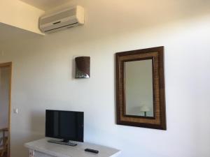 Golf Residence Apartment في فيلامورا: غرفة مع تلفزيون ومرآة على الحائط