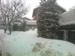 un patio cubierto de nieve frente a una casa en Къща за гости Типик, en Bansko