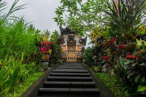 a stairway leading to a temple in a garden at Puri Astina Villa in Ubud