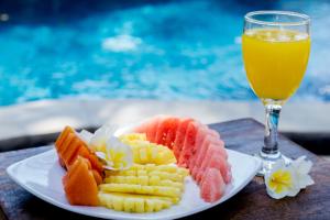 un plato de frutas y hortalizas y un vaso de zumo de naranja en Gili Breeze Tropical Bungalows, en Gili Trawangan