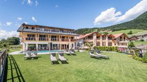 un groupe de chaises sur une pelouse devant un bâtiment dans l'établissement Sonus Alpis - Adults Only, à Castelrotto