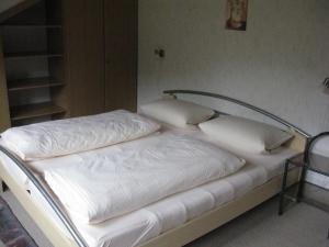 un letto con lenzuola e cuscini bianchi di Ferienwohnung Karlsruh a Warmensteinach