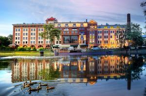 un groupe de canards dans l'eau devant un bâtiment dans l'établissement Hotel Słoneczny Młyn, à Bydgoszcz