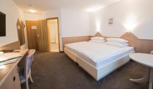 1 dormitorio con 1 cama blanca grande y escritorio en Hotel am Wasen, en Freiberg am Neckar