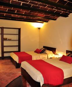 a hotel room with two beds with red sheets at Hotel Naira in La Paz