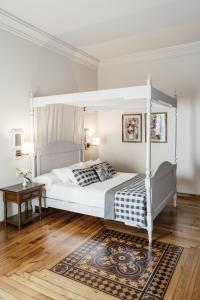 - une chambre blanche avec un lit à baldaquin blanc et un tapis dans l'établissement Parador de Baiona, à Baiona