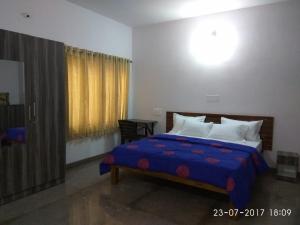 1 dormitorio con 1 cama con edredón azul en Aashraya Homestay, en Mysore