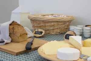 uma mesa com uma tábua de cortar com queijo e uma cesta em Villa Viriditas em Elbingerode